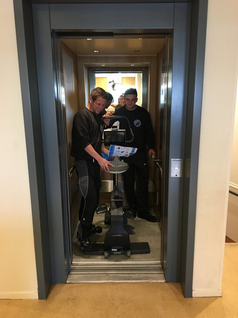Bezorgers Fitshop in de lift met hometrainer